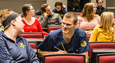 Two nursing students talk to each other in a classroom